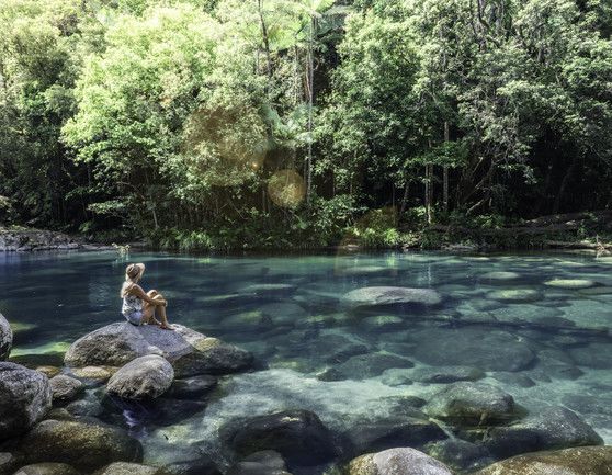 A woman sitting On A Rock Next To A River